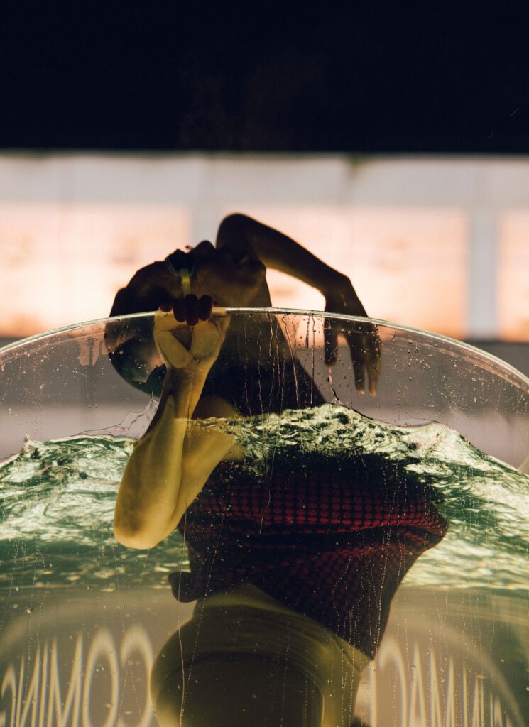 Woman in a water tank performing a kind of dance on the surface of the water