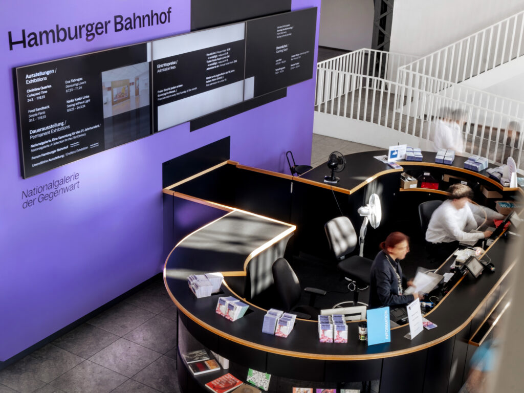 Round museum reception and ticket sales made of black wood. In the background is the 